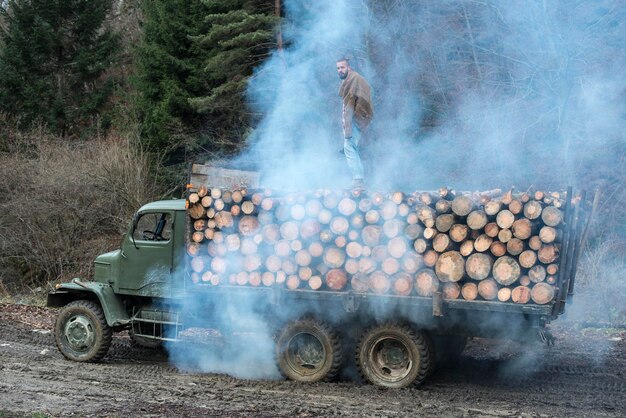 Foto ein junger mann steht auf einem stapel holzstämme auf einem lkw