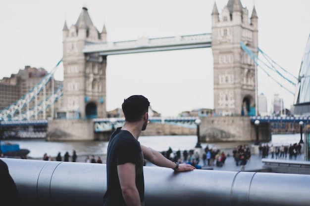 Foto ein junger mann steht auf einer brücke vor einem klaren himmel in der stadt