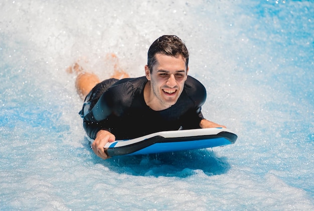 Ein junger Mann surft auf einem Wellen-Simulator in einem Wasser-Vergnügungspark