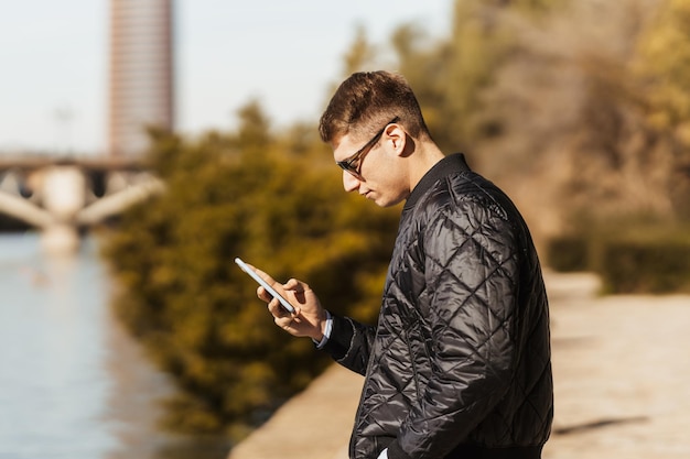 Ein junger Mann tippt sein Handy einhändig am Fluss People