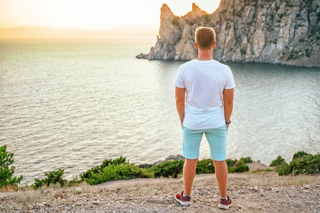 Ein junger Mann Tourist am Kap Kapchik in der Krim-Seelandschaft bei Sonnenuntergang