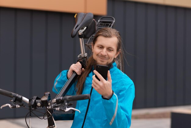 Ein junger Mann trägt sein Fahrrad die Straße hinunter und macht ein Selfie in hoher Qualität