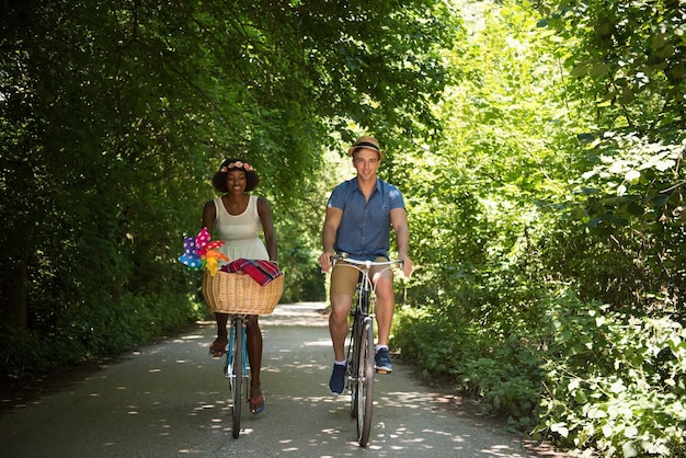 ein junger Mann und ein schönes afroamerikanisches Mädchen, das an einem sonnigen Sommertag eine Radtour in der Natur genießt