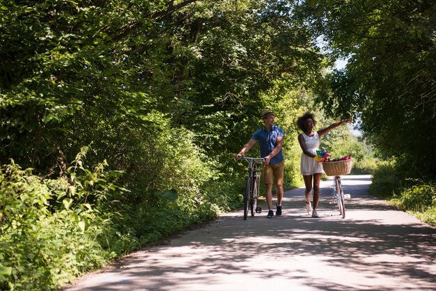 ein junger Mann und ein schönes afroamerikanisches Mädchen, das an einem sonnigen Sommertag eine Radtour in der Natur genießt