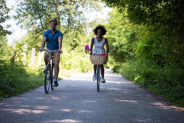 ein junger Mann und ein schönes afroamerikanisches Mädchen, das an einem sonnigen Sommertag eine Radtour in der Natur genießt