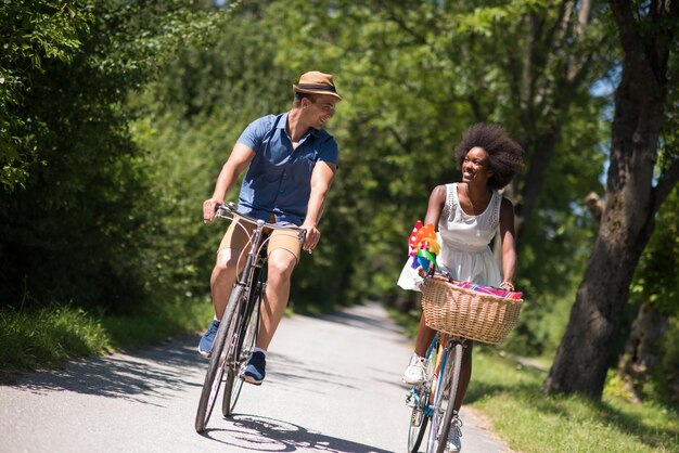 ein junger Mann und ein schönes afroamerikanisches Mädchen, das an einem sonnigen Sommertag eine Radtour in der Natur genießt