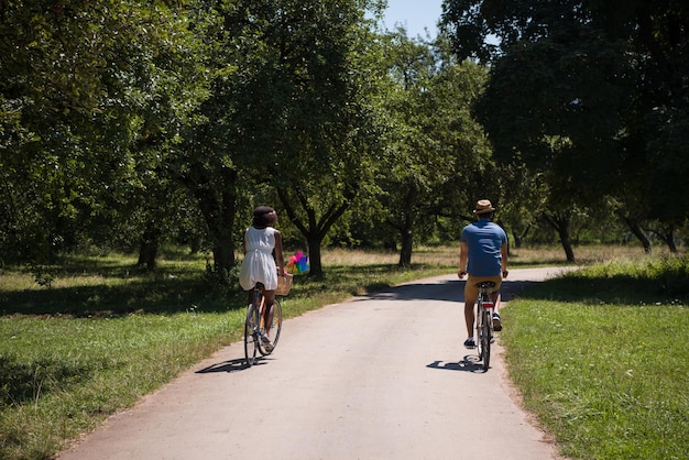 ein junger Mann und ein schönes afroamerikanisches Mädchen, das an einem sonnigen Sommertag eine Radtour in der Natur genießt