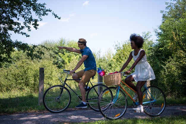 ein junger Mann und ein schönes afroamerikanisches Mädchen, das an einem sonnigen Sommertag eine Radtour in der Natur genießt