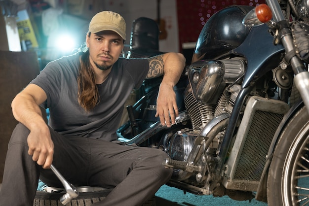Ein junger Mechaniker repariert ein Oldtimer-Motorrad Portrait Nahaufnahme