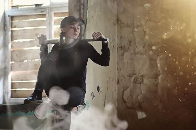 Ein junger Mensch mit Baseballschläger und Skateboard in einem verlassenen Haus