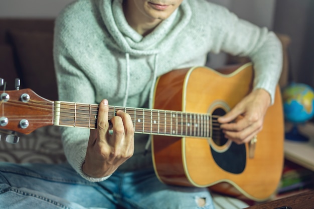 Ein junger Musiker lernt Akustikgitarre zu spielen