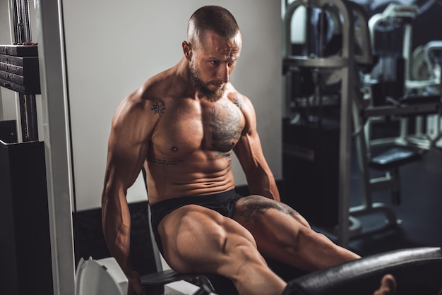 Ein junger muskulöser Bodybuilder, der im Fitnessstudio hart für seine Beinmuskeln trainiert.