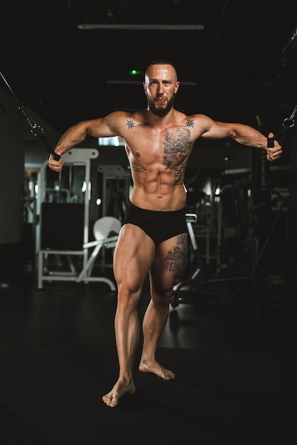 Ein junger muskulöser Bodybuilder, der im Fitnessstudio hart für seine Brustmuskeln trainiert.