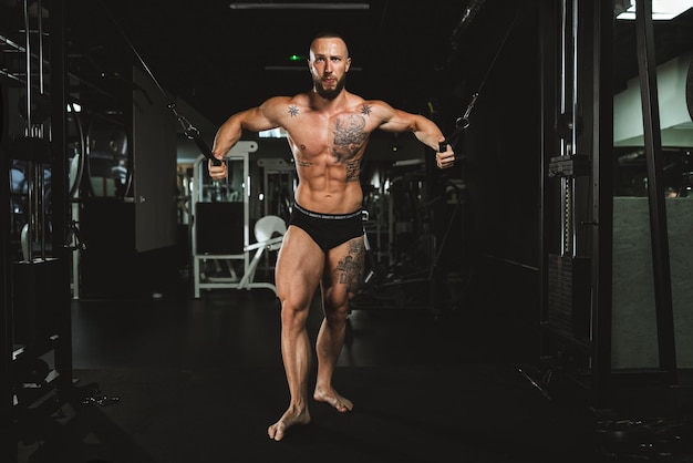 Ein junger muskulöser Bodybuilder, der im Fitnessstudio hart für seine Brustmuskeln trainiert.