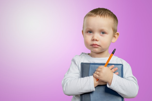 Ein junger Schuljunge hält ein blaues Buch