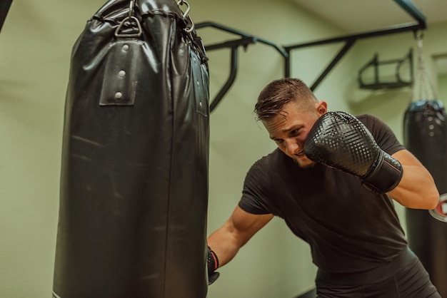 Ein junger sportlicher Mann trainiert intensiv, während er in einem Fitnessstudio einen Boxsack schlägt