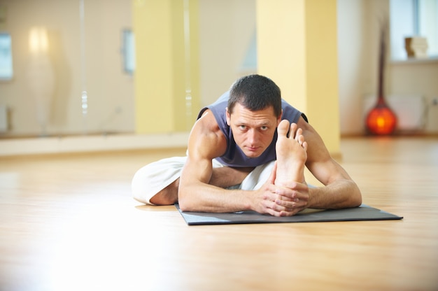 Ein junger starker Mann, der Yogaübungen macht. Ardha Padma Paschimottanasana sitzt vor der halben Lotusbiegung