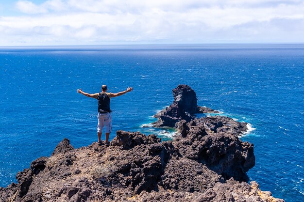 Ein junger Tourist auf dem Klippenweg beim Abstieg zum schwarzen Sandstrand von Bujaren, nördlich der Insel La Palma, Kanarische Inseln. Spanien