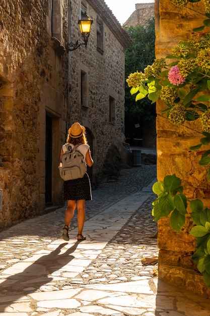 Ein junger tourist, der bei sonnenuntergang in den mittelalterlichen straßen von pals im historischen zentrum spazieren geht