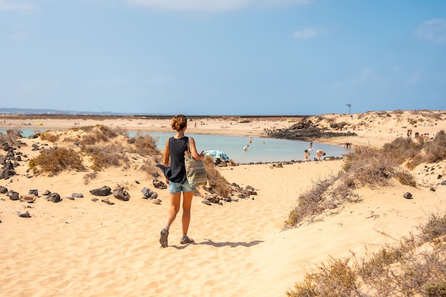 Ein junger Tourist, der den Strand von La Concha auf der Isla de Lobos besucht, neben der Nordküste der Insel Fuerteventura, Kanarische Inseln. Spanien