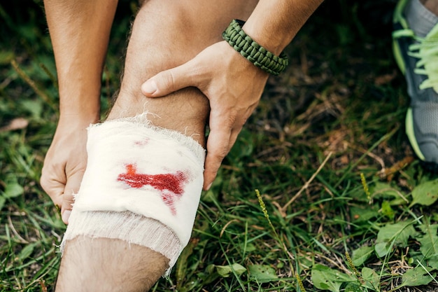 Ein junger Tourist mit einem Verband verbindet die Verletzung an seinem Bein auf dem Weg zum Camp