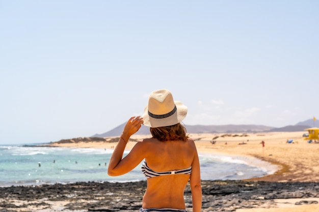 Ein junger Tourist mit Hut an den Stränden des Naturparks Corralejo, Fuerteventura, Kanarische Inseln. Spanien