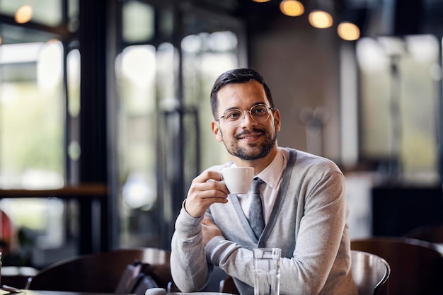 Ein junger trendiger Mann in Smart Casual sitzt im Café und trinkt seinen Espresso