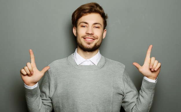 Ein junger und hübscher Geschäftsmann, der mit dem Finger nach oben zeigt