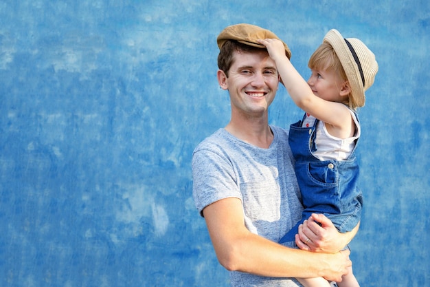 Ein junger Vater hält seine Tochter an den Händen, lacht und hat Spaß an einem sonnigen Sommertag