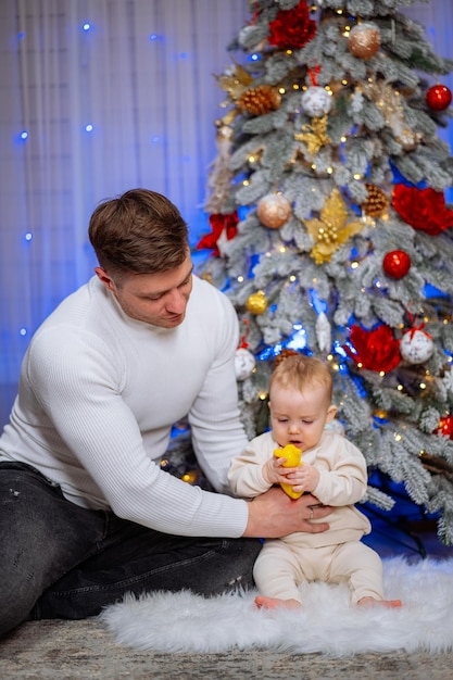 Ein junger Vater spielt mit seinem kleinen Sohn in der Nähe des Weihnachtsbaums