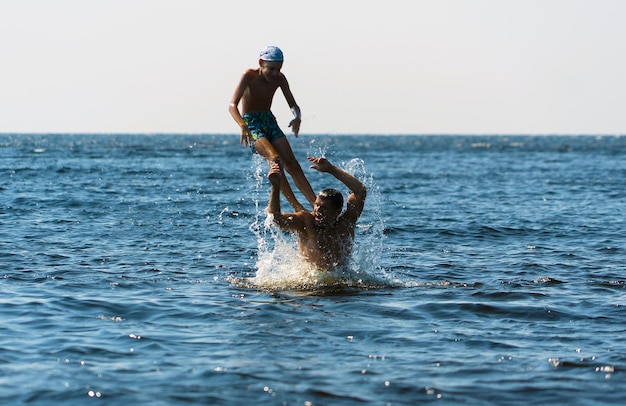 Ein junger Vater wirft seinen Sohn von den Schultern ins Wasser des Ladogasees