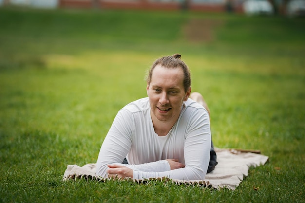 Ein junger Yogalehrer entspannt sich im Park vor dem Üben, Sommer