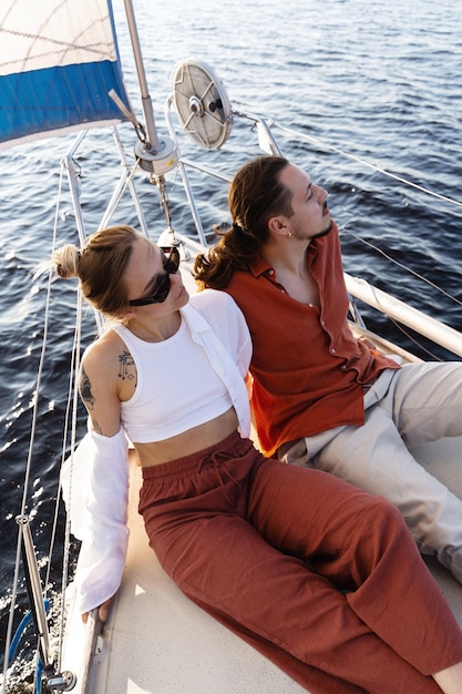 Ein junges attraktives Paar entspannt sich auf dem Segelboot, während es auf dem Meer segelt