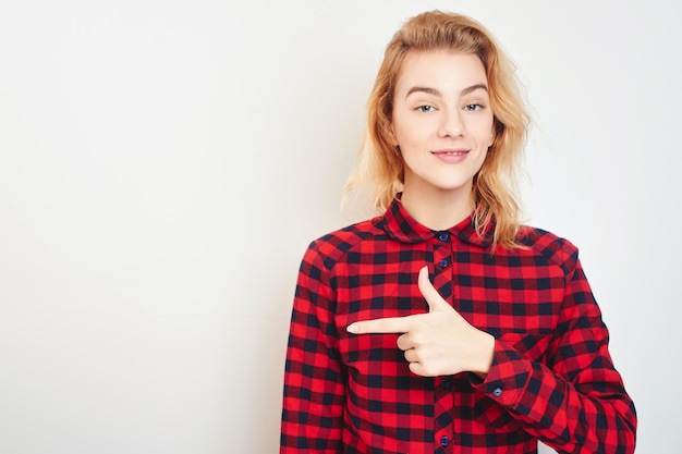 Ein junges blondes Mädchen im roten Hemd zeigt mit dem Finger im Hintergrund