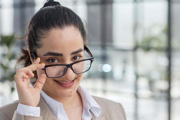 Ein junges erwachsenes Mädchen passt sanft ihre Brille an. Leidenschaftlicher Blick in die Linse