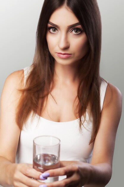 Ein junges gesundes Mädchen trinkt Wasser aus dem Glas