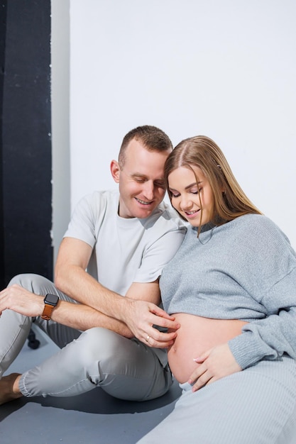 Ein junges glückliches Ehepaar freut sich über Schwangerschaft und Umarmung auf weißem Hintergrund Ein glücklicher Ehemann und eine Ehefrau sind schwanger und erwarten ein Kind