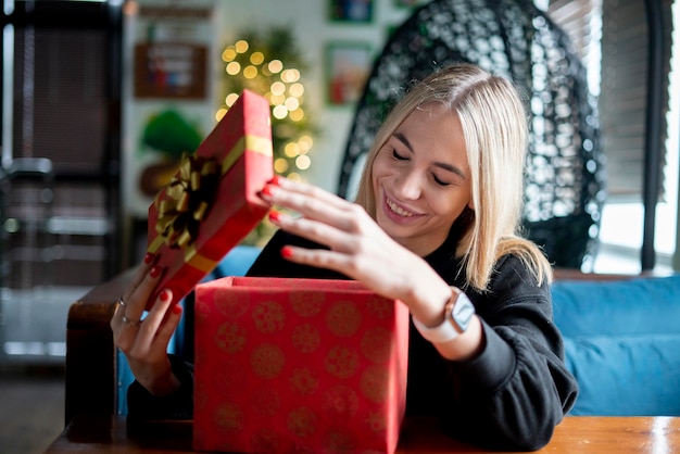 Ein junges glückliches Mädchen öffnet die rote Geschenkbox