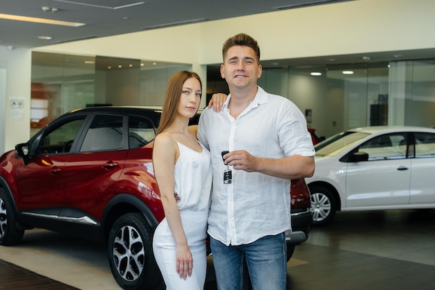 Ein junges glückliches Paar freut sich, ein neues Auto zu kaufen. Autokauf.