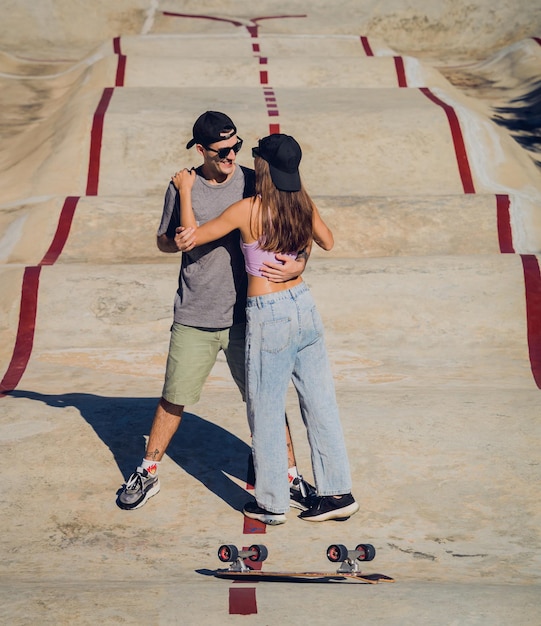 Ein junges, glückliches Paar mit Skateboards macht Longboarding im Skatepark