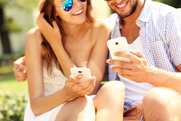 ein junges glückliches Paar mit Smartphones im Park