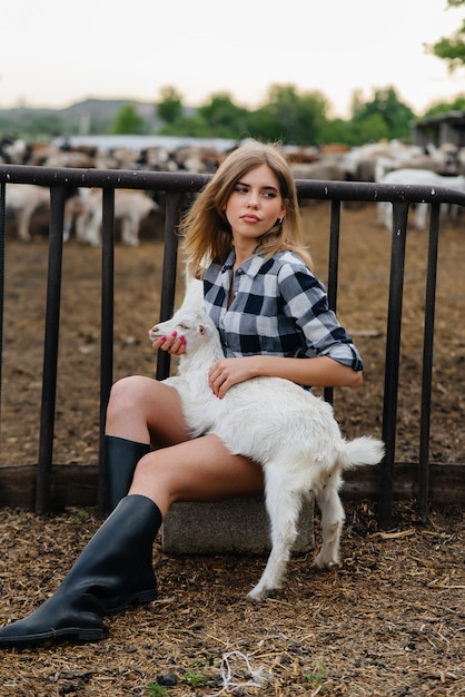 Ein junges hübsches Mädchen posiert auf einer Ranch mit Ziegen und anderen Tieren. Landwirtschaft, Viehzucht.