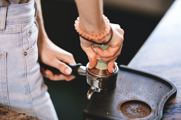 Foto ein junges, hübsches, schlankes mädchen, das ein lässiges outfit trägt, kocht kaffee in einem modernen café. es konzentriert sich auf den prozess. .