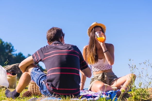 Ein junges kaukasisches Paar, das beim Picknick in den Bergen am Meer etwas Schinken isst