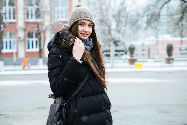 Ein junges langhaariges Mädchen in einer warmen Jacke geht bei Winterwetter durch die Straßen der Stadt