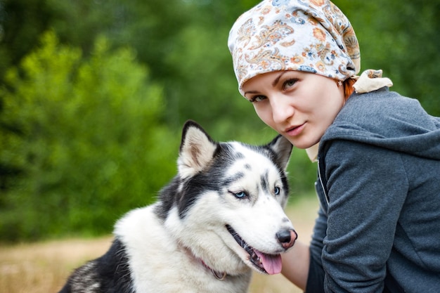 Ein junges Mädchen beim Spaziergang im Park mit einem Hund, der den Hund Husky umarmt und küsst