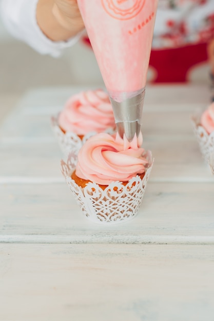 Ein junges Mädchen dekoriert Cupcakes mit Sahne.