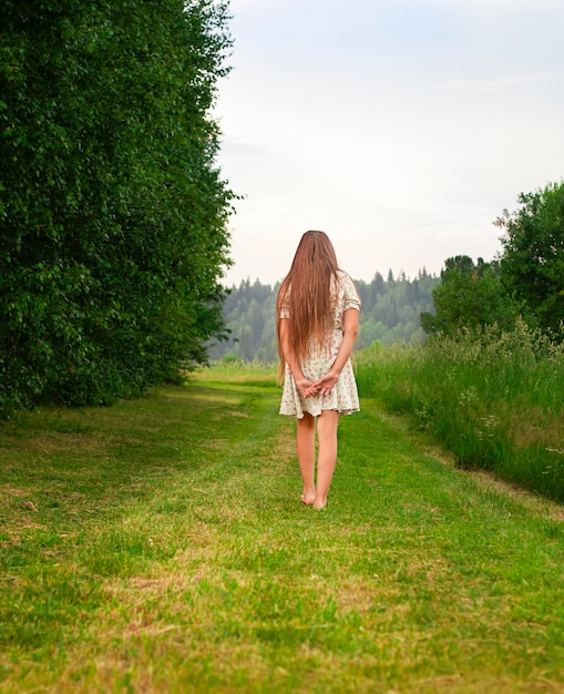 Ein junges Mädchen geht im Sommer auf einer grünen Wiese