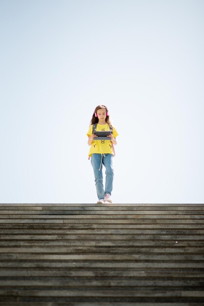 Ein junges Mädchen geht mit einem Gadget in der Hand die Treppe hinunter Generation Z Lifestile