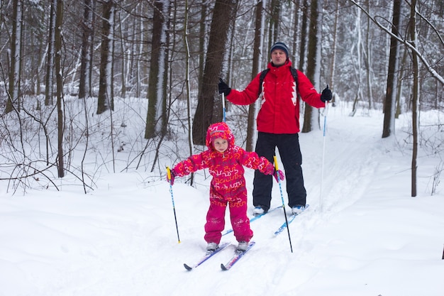 Ein junges Mädchen im roten Anzug lernt Skifahren